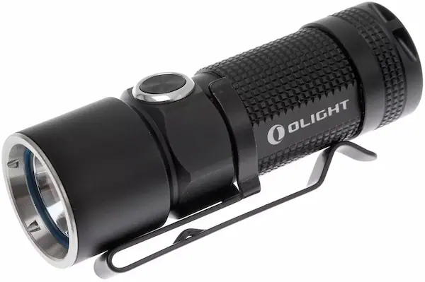 Olight S10 Baton flashlight. It's black and small, maybe 7 cm. It has a clip to attach it to clothes. The small power button is on the side. Back half of the flashlight is textured to give it some grip.